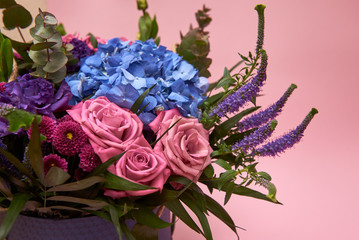 Beautiful bouquet of pink, purple and blue flowers in big violet hat box on pastel pink background, copy space. Greeting card for Womens Day, Mothers Day, Valentines Day, wedding, birthday