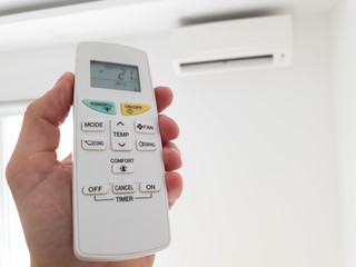 Modern airconditioner unit with a hand holding a remote.