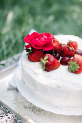 Delicious rustic hand made white fluffy cake with fresh strawberries and cherries on the top.
