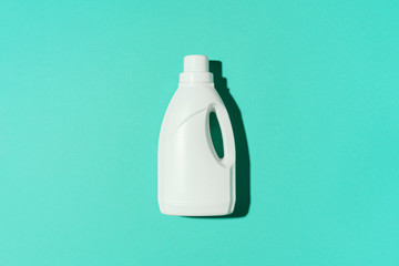 White plastic bottle of cleaning product, household chemicals or liquid laundry detergent on blue background. Top view. Flat lay. Copy space. Detergent bottle