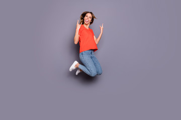Full body photo of cheerful girl teenager visit weekend heavy metal concert jump make horned symbol jump show tongue out wear jeans denim white sneakers isolated grey color background