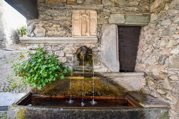 Close-up of the stone fountain of the Truei (fontana del Truei), dating back to the sixteenth century in the alpine village of Casteldelfino, Cuneo, Varaita Valley, Piedmont, Italy 