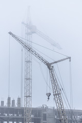 Construction crane in foggy weather on the construction of residential buildings.