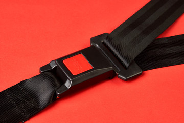 Fastened seat belt on red background with copy space, close-up