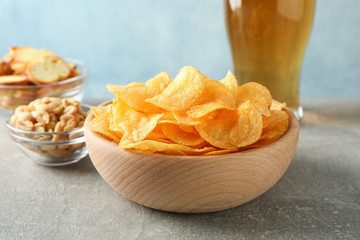 Potato chips in a bowl and glass of beer. Beer snacks, beer nuts on grey table against blue background, space for text. Closeup