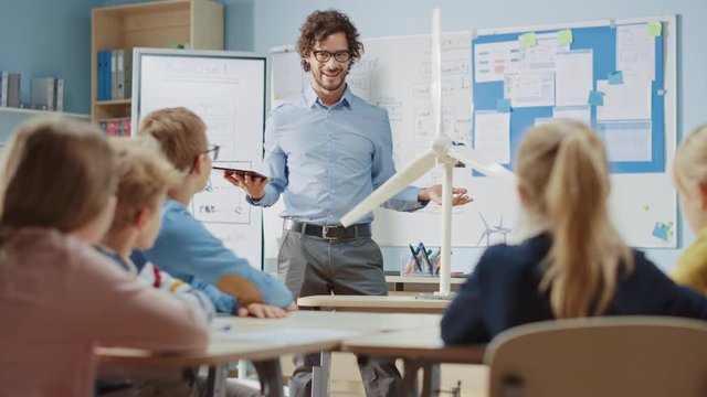 Elementary School Physics Teacher Uses Interactive Digital Tablet to Show to a Classroom of Smart Children how Renewable Energy and Wind Turbines Works. Science Class with Kids Listening Attentively
