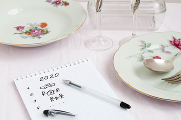 Plans for 2020 write in notebook notebook lies on the table near are worth beautiful festive plates a fork and spoon