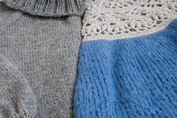Fototapeta na wymiar Two knitted pullovers gray with a high neck and blue with openwork knit lie next to each other