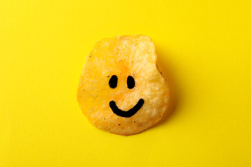 Potato chips with smile on yellow background, space for text. Top view