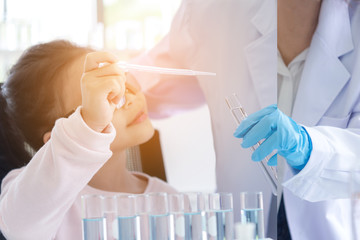 Asian children analyzing study evaluating microscope with scientist. Health care researchers doing...