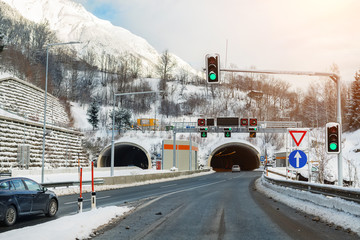 Winter alpine road landscape with tunnel, forest, mountains and blue sky on background at bright...