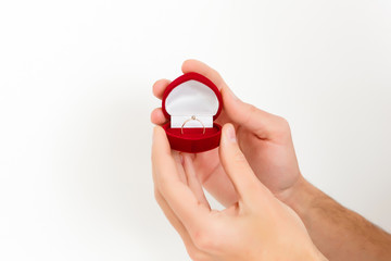 red gift box in the form of heart with a ring inside in female hands on a white background