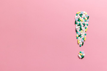 Composition of pills and capsules on a pink background in the form of an exclamation mark. Psychological help. Copy space. View from above. Flat lay.