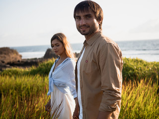 Obraz premium Attractive couple on vacation on the shore of the ocean at sunset time