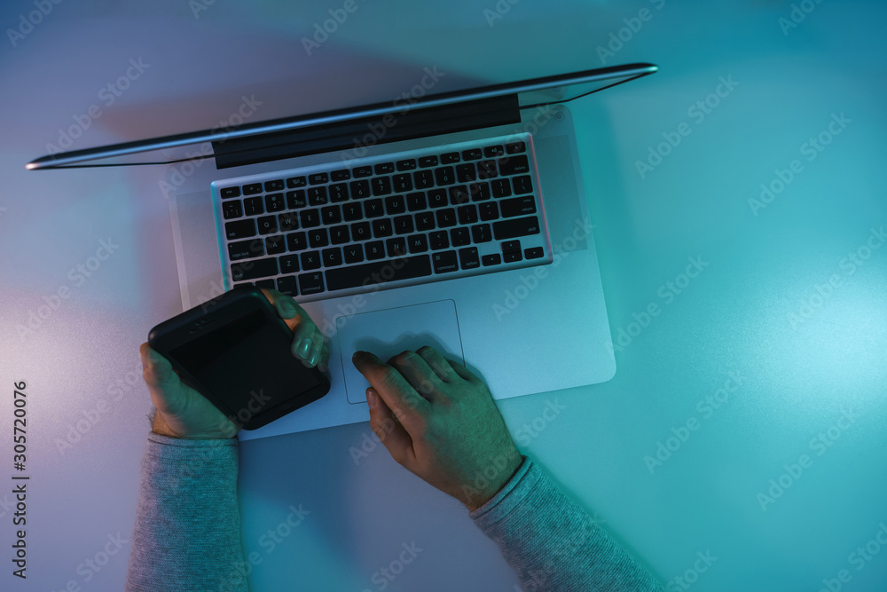 Aufkleber man working night online silver laptop and smart phone in the color light on a table night backgroun