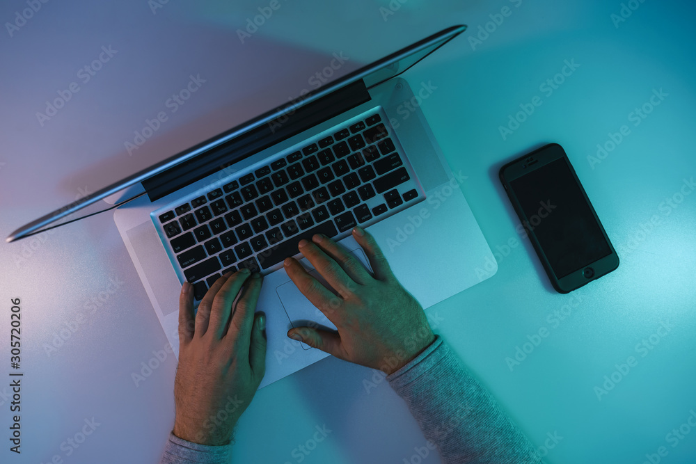 Aufkleber man working night online silver laptop and smart phone in the color light on a table night backgroun