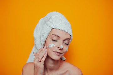 Young woman in white towel on head on the orange background. Woman in bath with clean and soft skin...