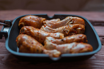 Raw chicken drumsticks in sauce and spices in a pan not a wooden background.