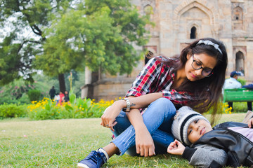 Young Girl with baby boy sitting in the park. Siblings spending time together in garden.