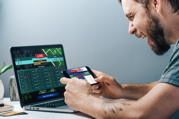 Guy being happy winning a bet in online sport gambling application on his mobile phone