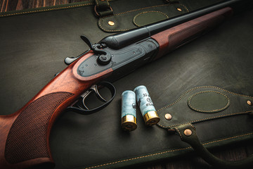 Classic trigger double-barreled hunting rifle on a green background. Smooth-bore hunting rifle open...