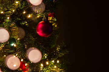 Closeup of Christmas tree with lights, balls and decorations, dark background