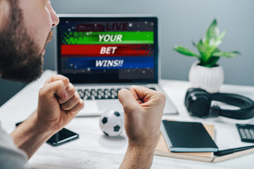 Guy being happy winning a bet in online sport gambling application on his mobile phone