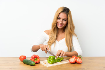 Young blonde woman with vegetables in a table