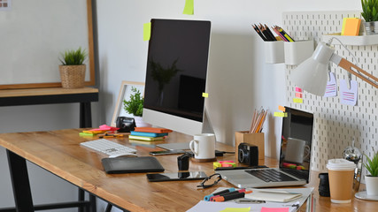 Graphic designer workspace with computer and creative accessories on table.
