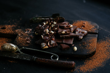 Slices of milk chocolate with nuts and dried fruits on a wooden board