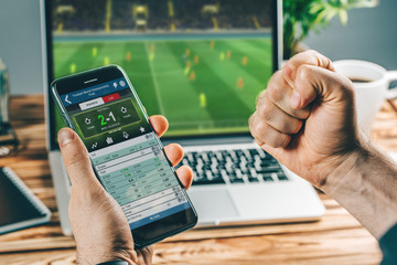 Man watching football play online broadcast on his laptop, cheering for his favourite team, making bets at bookmaker's website - 305726495