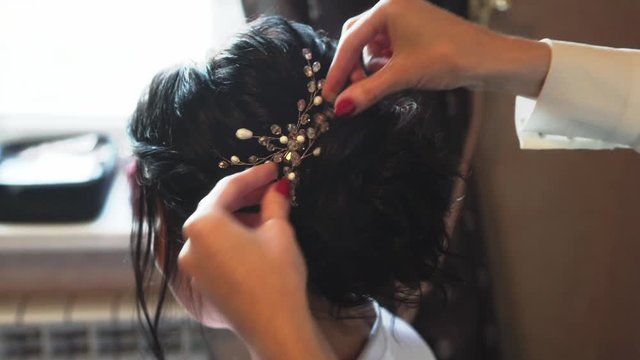 Makeup artist does hairstyle to bride before wedding