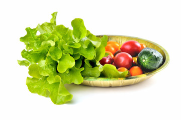 lettuce yellow and red tomatoes, cherry tomatoes and cucumber on a vintage dish white background, isolate, front view