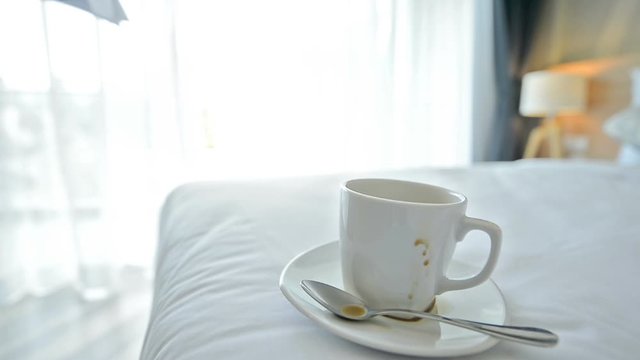 Busy day.Stack papers and coffee cups placed on the bed in the businessman's bedroom. The hand holding the document and bills quickly makes it known that it is a very busy day for this businessman.