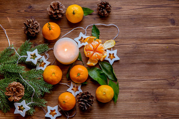 Christmas and new year decor. Christmas card. Tangerines, candle, lights, cones on a wooden background