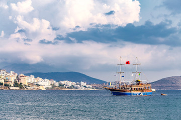 Obraz premium Vintage mast wooden sailing ship for sea tours in port of Saranda, Albania with red state albanian flag with black double-headed eagle, and italian flag and The Flag of Europe or European Flag