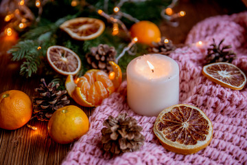 Fototapeta na wymiar Christmas and new year decor. Christmas card. Tangerines, candle, lights, cones on a wooden background