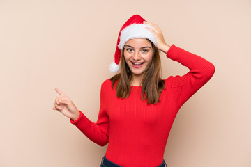 Young girl with christmas hat over isolated background surprised and pointing finger to the side