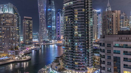 Aerial view of Dubai Marina residential and office skyscrapers with waterfront night timelapse