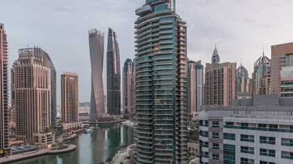 Obraz premium Widok z lotu ptaka wieżowców mieszkalnych i biurowych Dubai Marina z nabrzeża noc do dnia timelapse