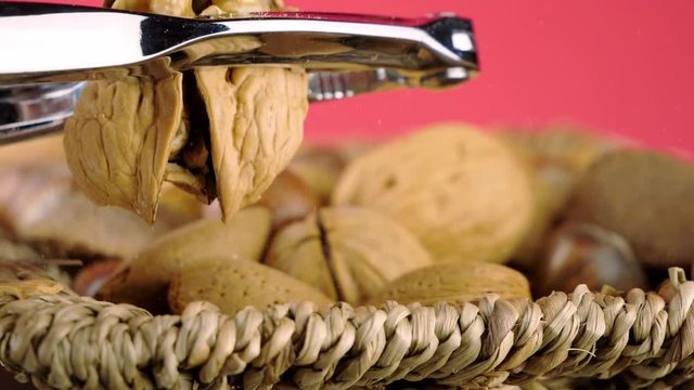 Macro view of a metal nut cracker tool in operation, as it splits a walnut in half