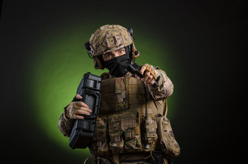 Fototapeta premium a male soldier in military clothes with a weapon on a dark background