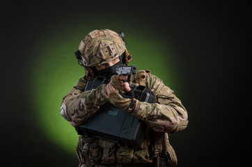 a male soldier in military clothes with a weapon on a dark background