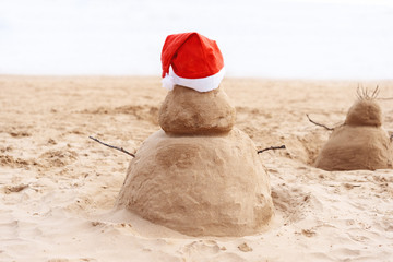 New Year or Merry Christmas sand snowman on ocean beach.