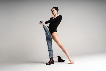 Obraz premium womens bodysuit, black boots, blue jeans. Tall sexy short haired model posing in a fashionable bow on a white background