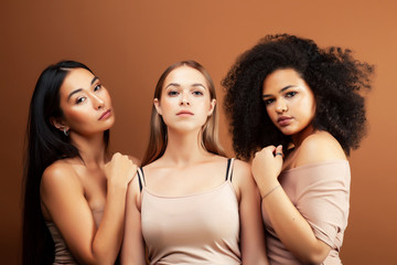 Obraz premium young pretty asian, caucasian, afro woman posing cheerful together on brown background, lifestyle diverse nationality people concept