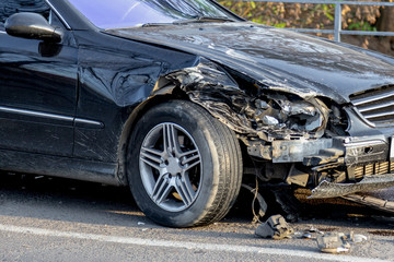Car accident closeup with a broken partial car and some messy liquids at the asphalt.