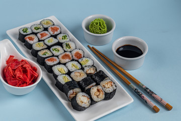 Sushi with fish, with cucumber, with eel, with avocado. Wrapped in Nori Seaweed. Food for vegetarians. Soy sauce, ginger, wasabi in white bowls. Copy space.