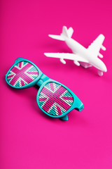 Turquoise sunglasses with United Kingdom flag in lenses on crazy pink background with white...