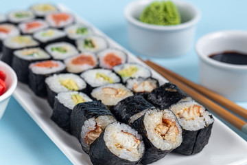 Sushi with fish, with cucumber, with eel, with avocado. Wrapped in Nori Seaweed. Food for vegetarians. Soy sauce, ginger, wasabi in white bowls. Copy space.